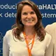 Smiling woman with long brown hair at a trade stand