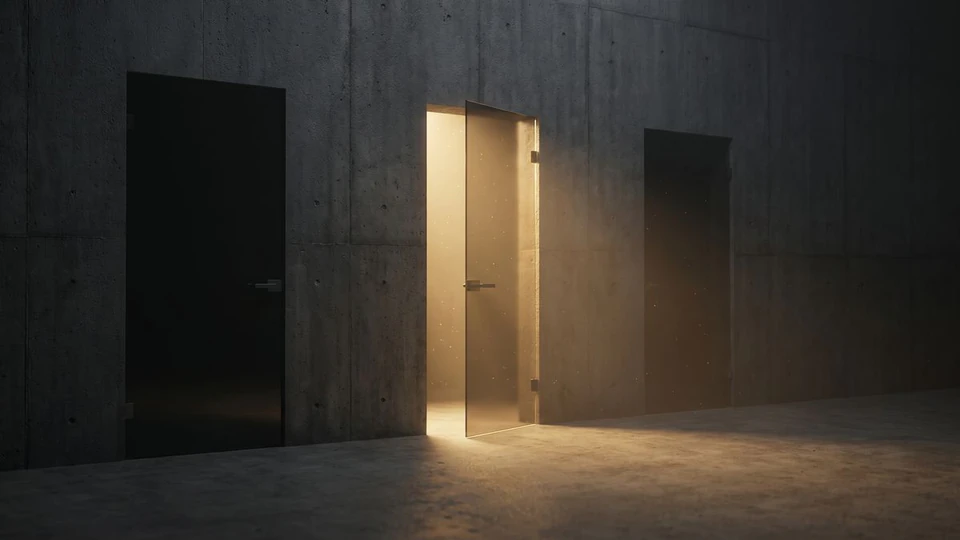 Three smoked glass doors in a concrete wall, the middle one open with gold light spilling out